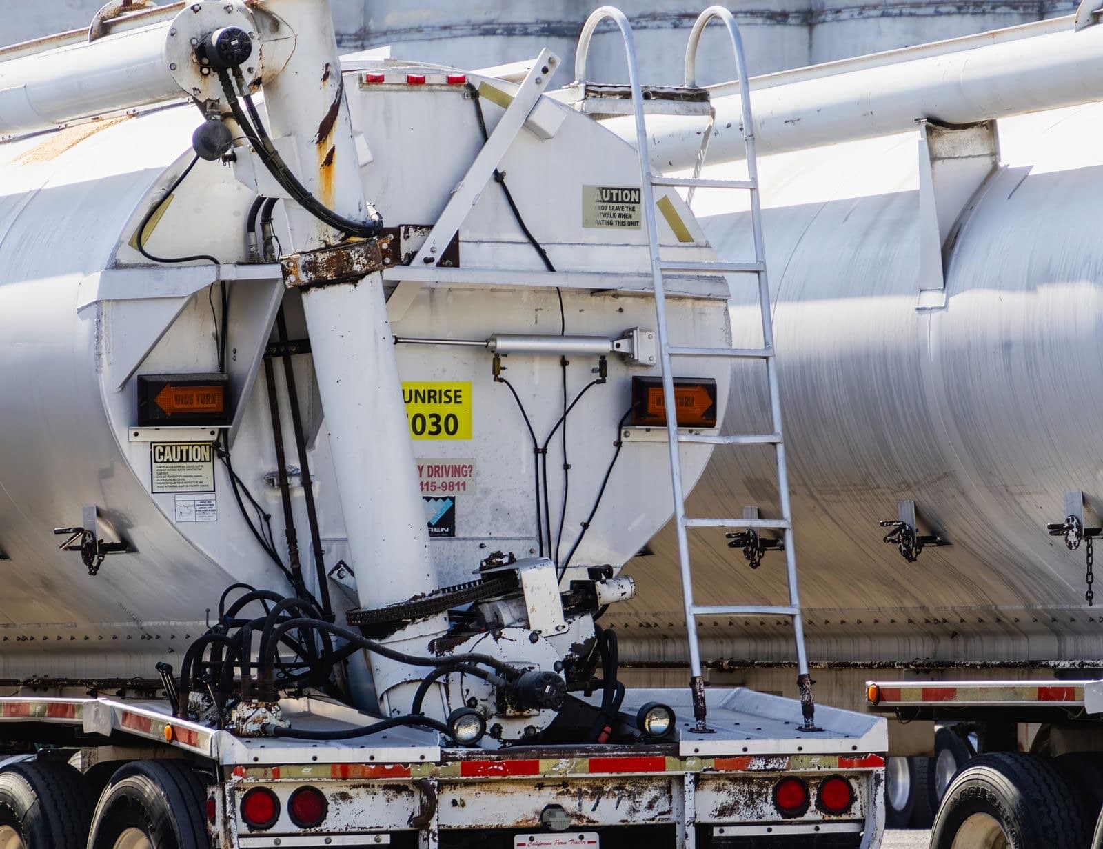 The rear of a road tanker, showing the transfer pump, hose connections and access ladder.