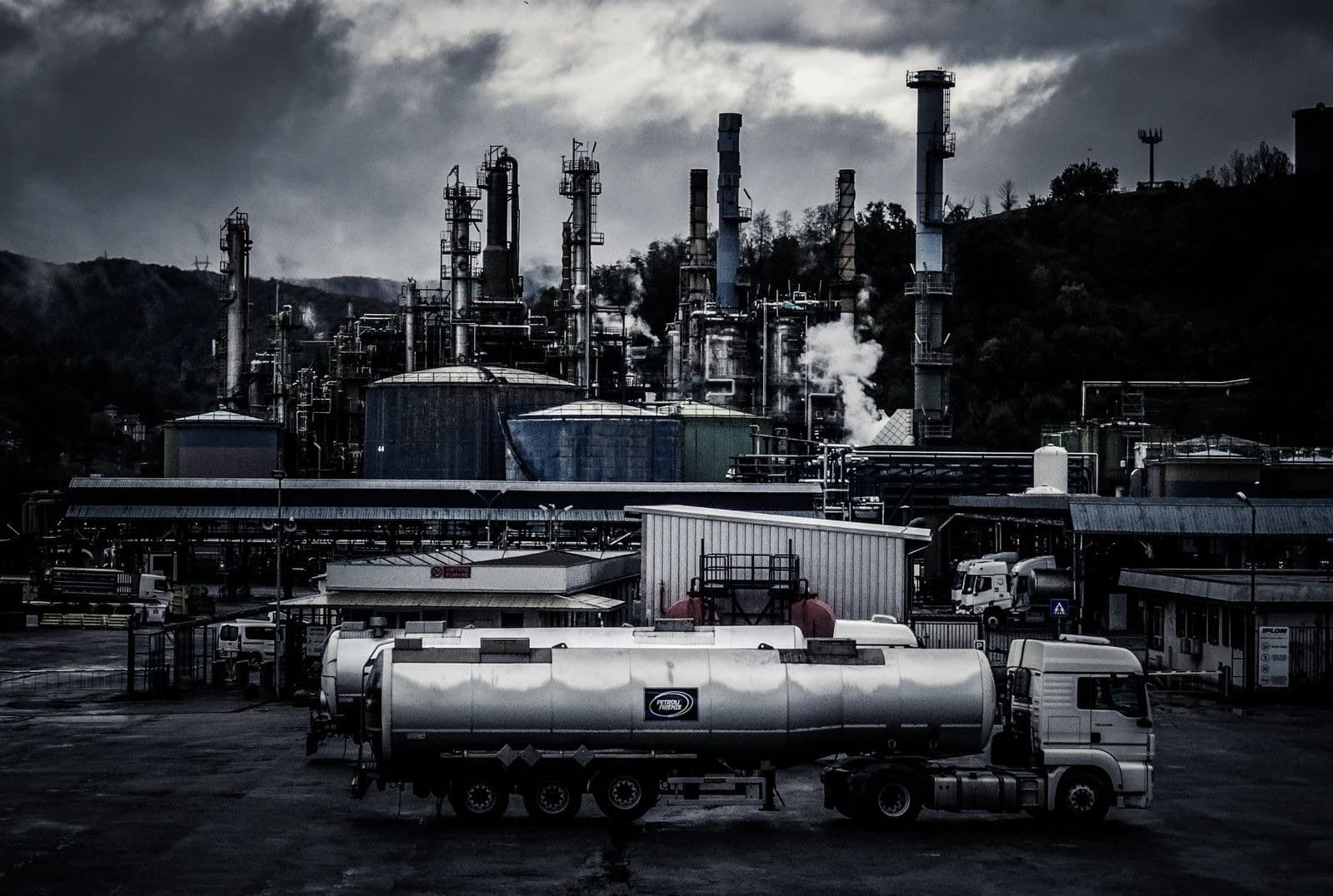 A storage and processing terminal at dusk, with a road tanker loading in the foreground.